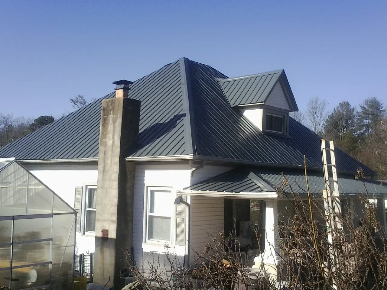 Dark blue standing seam metal roof on a white farmhouse with dormer — Slate & Tile Roof Repair by Roofing Brothers in Weaverville