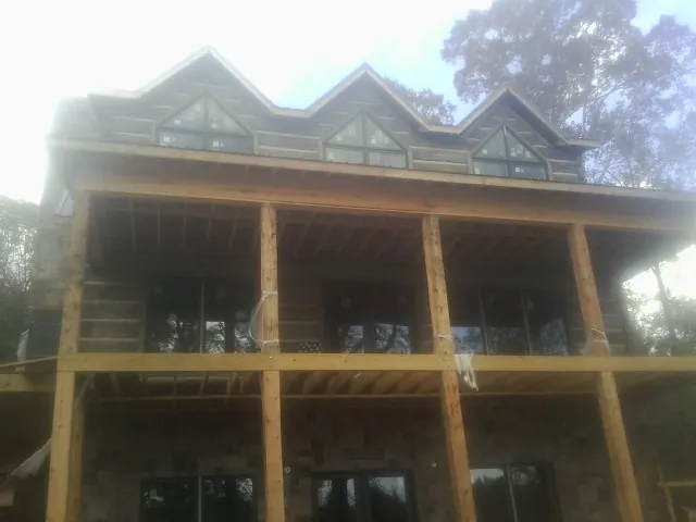 Dormers and porch framing on a large log home under construction — Roof Coating work by our crew in Weaverville