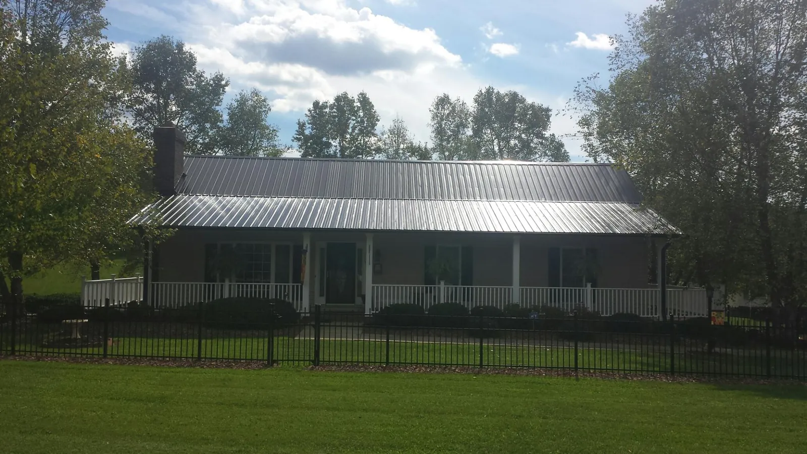 Gray metal roof on a brick ranch with a full width front porch — Gutter Guard Installation work by our crew in Weaverville