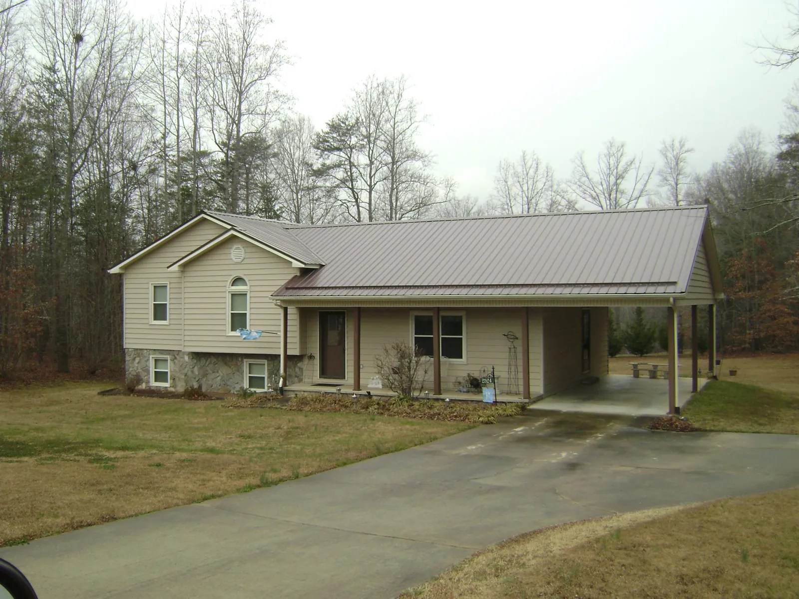 Brown metal roof on a tan split level home with an attached carport in Weaverville