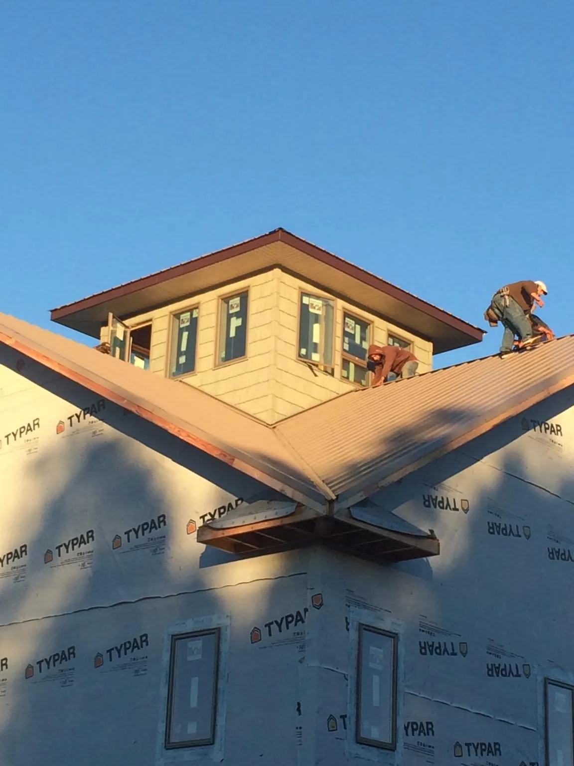 Roofers working around a rooftop cupola on a new metal roof at sunset — Roof Waterproofing in Weaverville by Roofing Brothers
